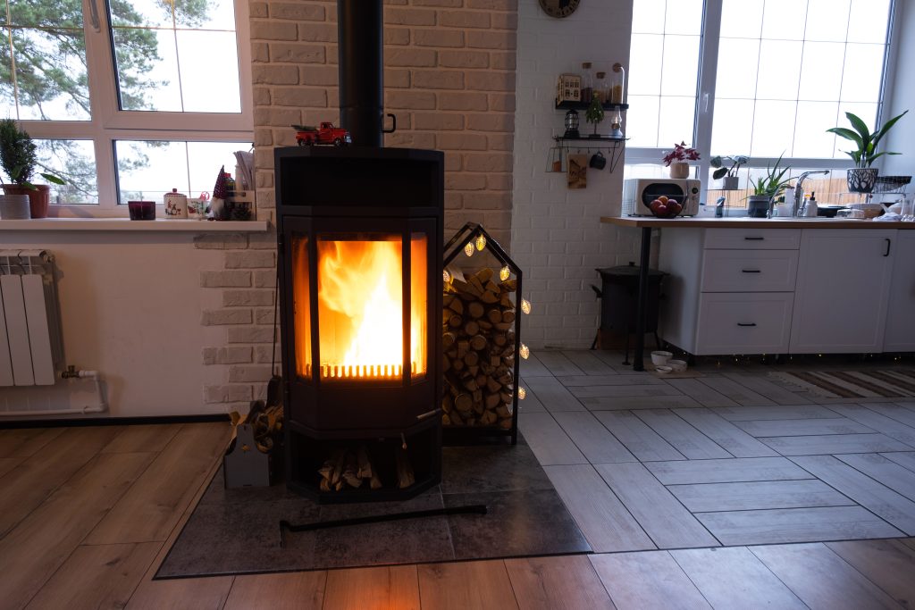 Black metal stove fireplace with wood in a woodpile - the interior of a private village house