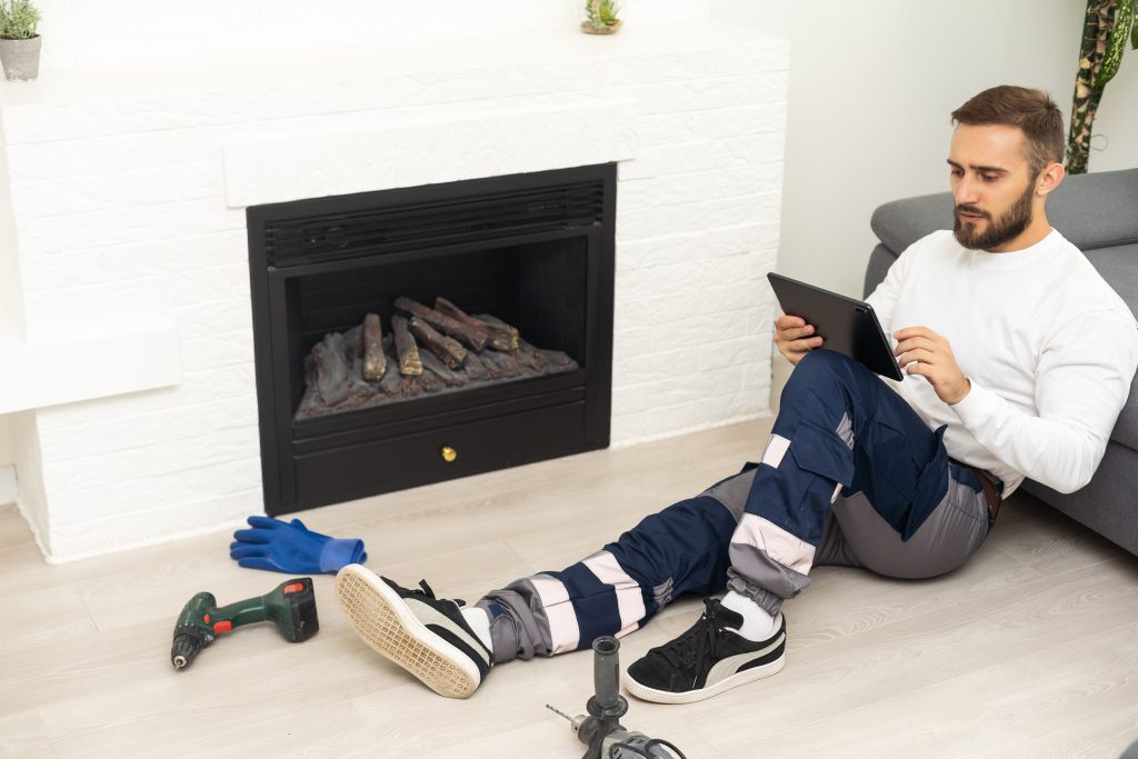 Service technician with tablet repairing a fireplace in a home