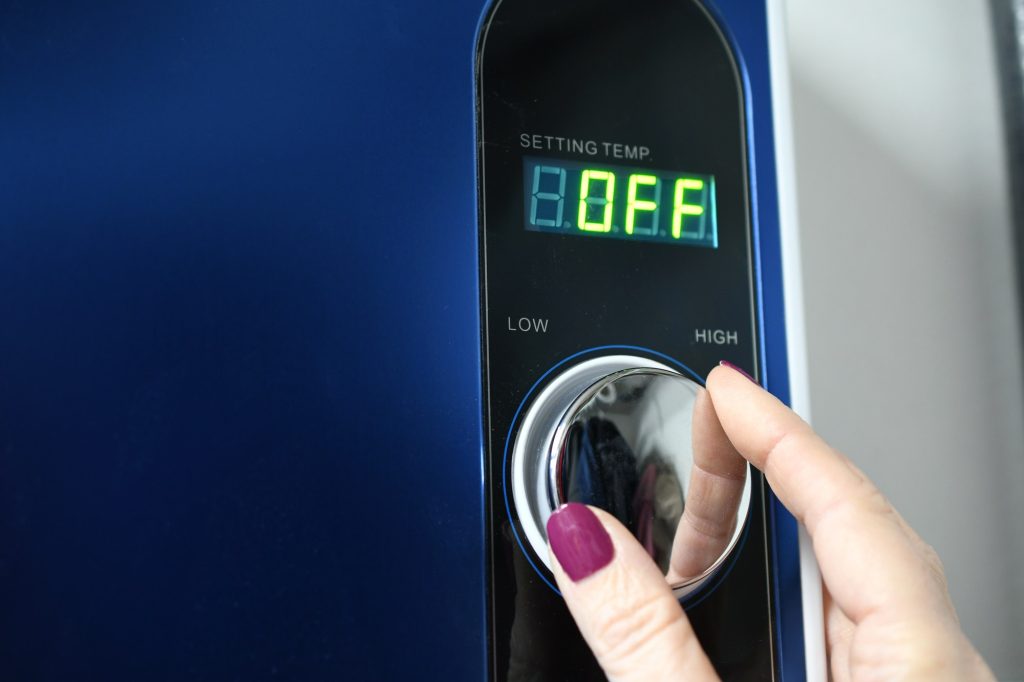 Female hand adjusting a tankless instant hot water heater. Energy efficient efficiency, conservation